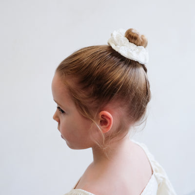 girl wearing giant broderie scrunchie in a bun hair style