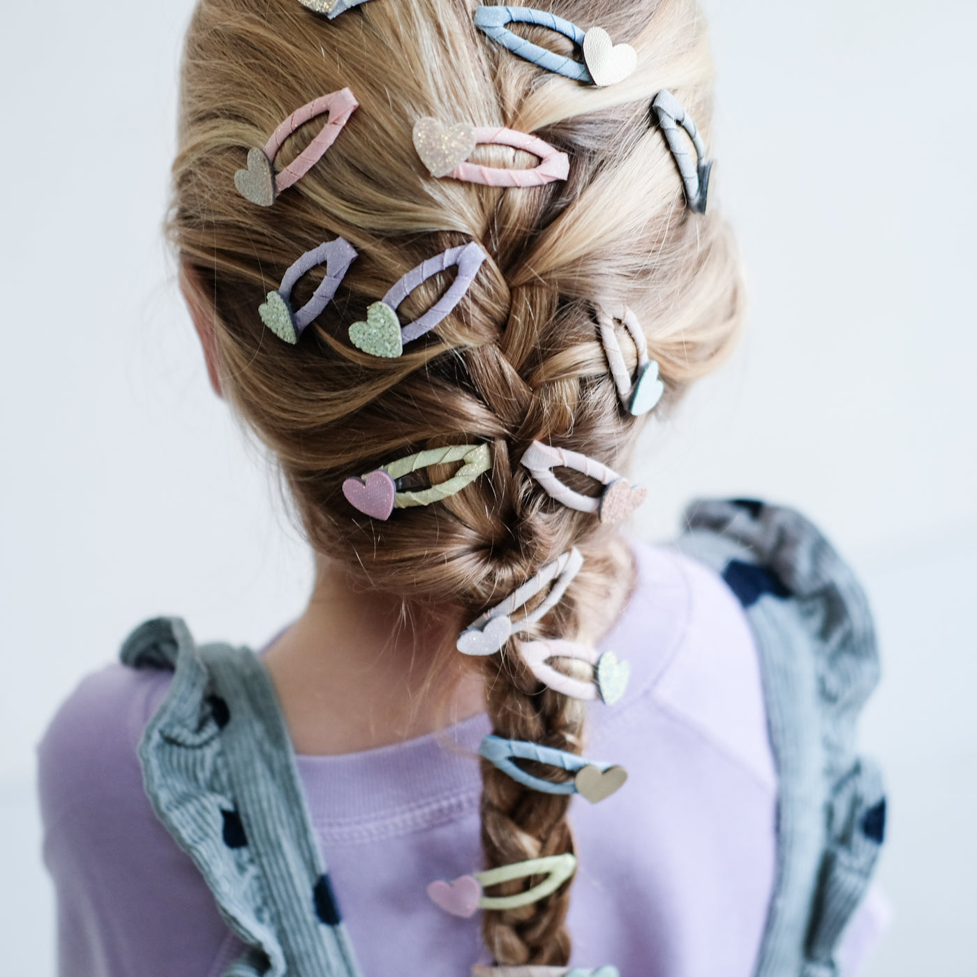 girl with her hair styled in a french plait with lots of heart mini clic clacs in it