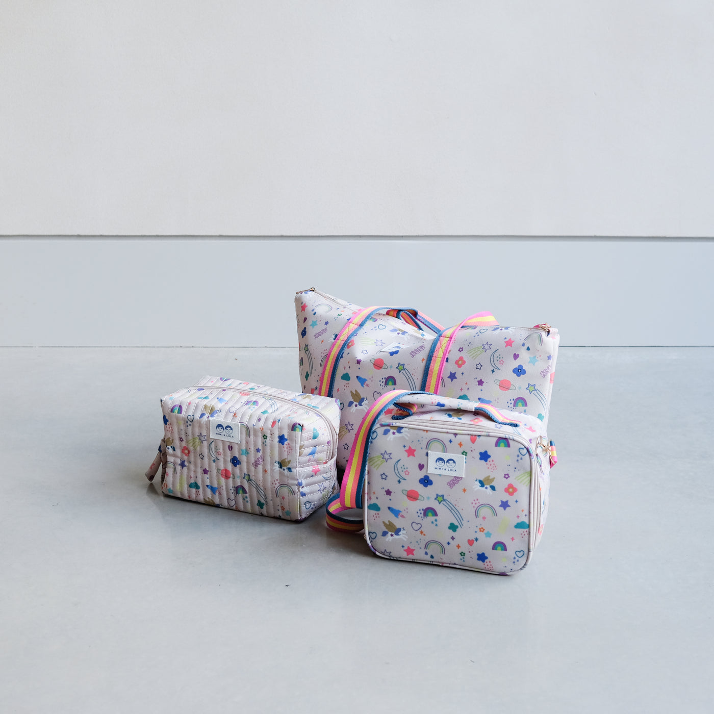 Trio of bags in a bright unicorn print fabric including a wash bag, lunch bag and holdall