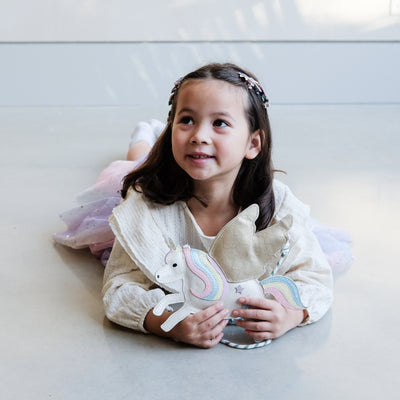 young girl holding a flying unicorn bag