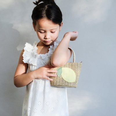 girl holding a lemon straw bag on her arm