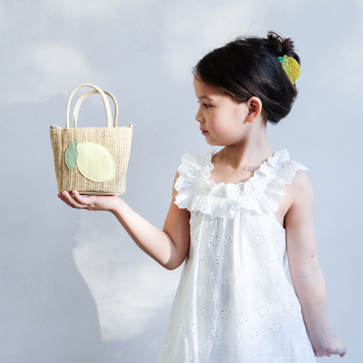 girl holding a lemon straw bag in her hand