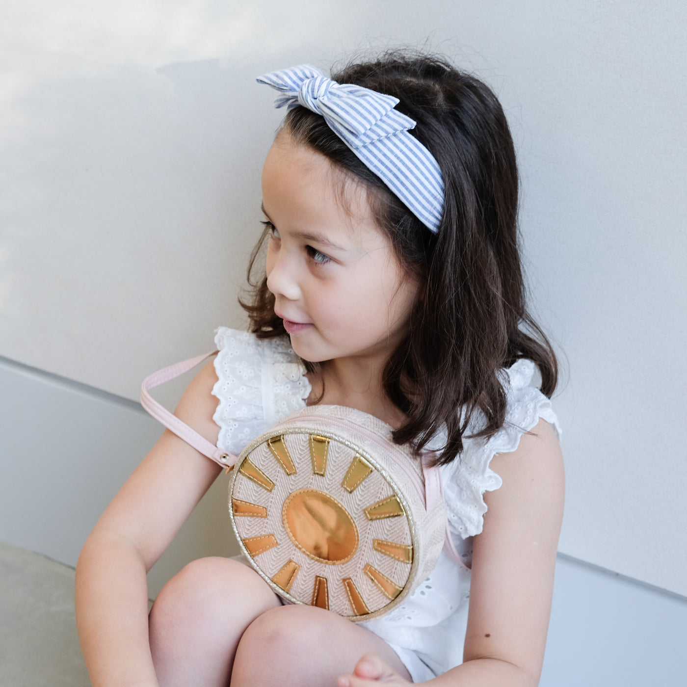 girl wearing sunshine bag and stripe alice band in hair