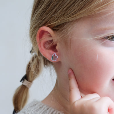 Close-up of a person wearing a pink heart-shaped earring with a blurred background