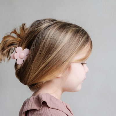 Little girl with relaxed looking up do held together with a pretty pale pink daisy bulldog clip