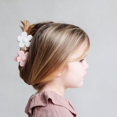 Super sweet updo style on dark blonde little girl using two daisy shaped bulldog clips in soft pink and cream