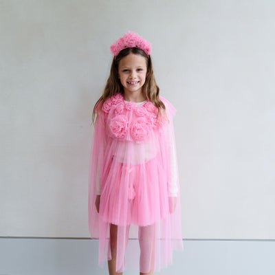 Video of young girl wearing a bright pink cape, tutu, wand, and floral ruffle headdress