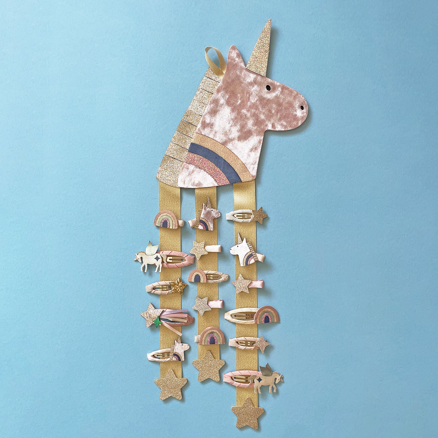 image of a unicorn hair clip hanger decorated with unicorn themed hair clips against a blue background
