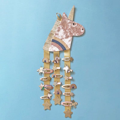 image of a unicorn hair clip hanger decorated with unicorn themed hair clips against a blue background